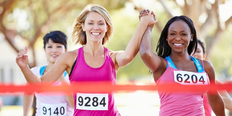 Runners holding hands while crossing finish line
