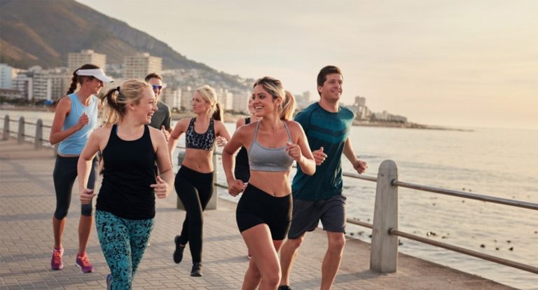 People running on a boardwalk next to the ocean