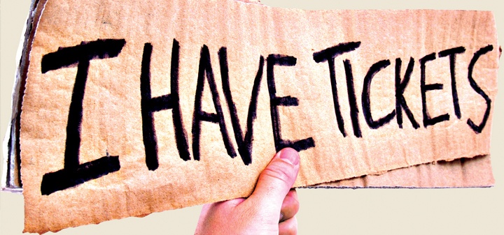 Hand holding cardboard sign showing I have Tickets